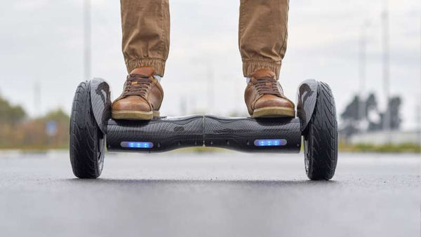 Ein Mann fährt mit dem E-Hoverboard auf einer Betonstraße.