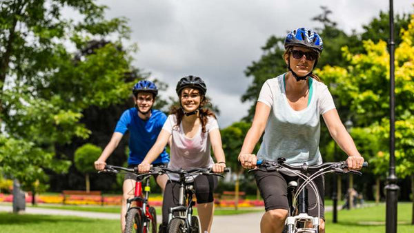 Eine Familie ist mit dem E-Bike im Park unterwegs