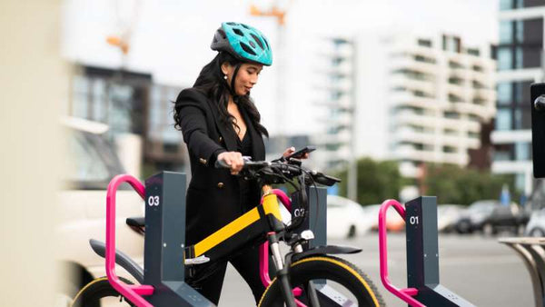 Eine Frau mit Helm fährt mit einem E-Bike durch die Stadt