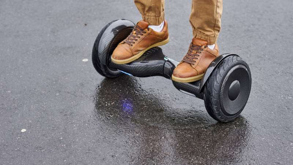 Eine Person auf dem E-Hoverboard auf einer Betonstraße.